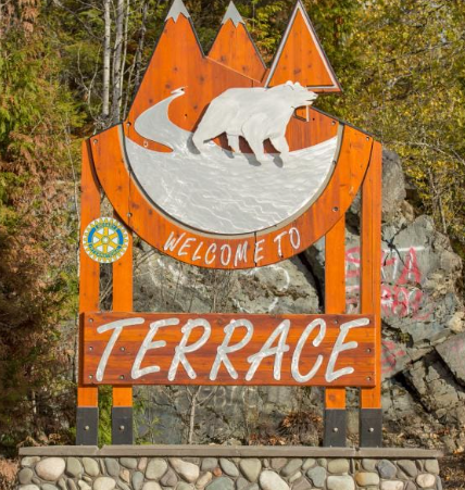 Wooden sign reading Welcome to Terrace, topped by orange mountain peaks and a white bear, with a Rotary emblem.